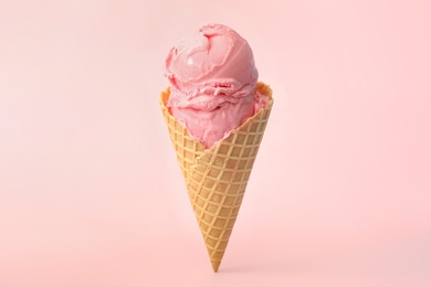 Photo of Delicious ice cream in waffle cone on pink background