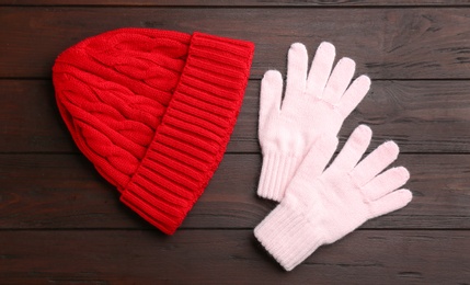 Stylish gloves and hat on wooden background, flat lay