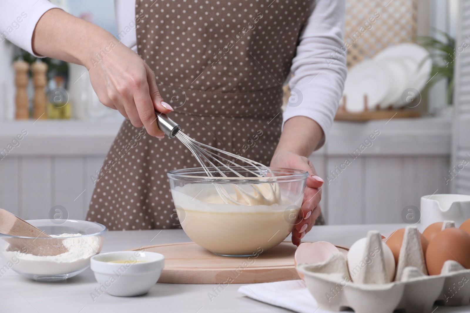 Photo of Woman making dough with whisk in bowl at table, closeup