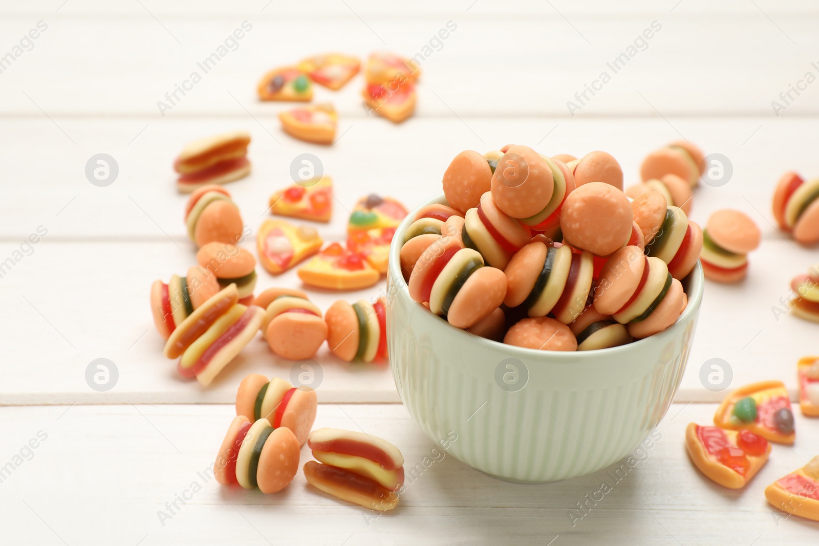 Photo of Many different delicious gummy candies on white wooden table