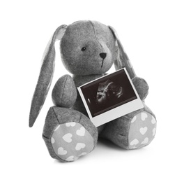 Photo of Ultrasound photo of baby and toy rabbit on white background. Concept of pregnancy