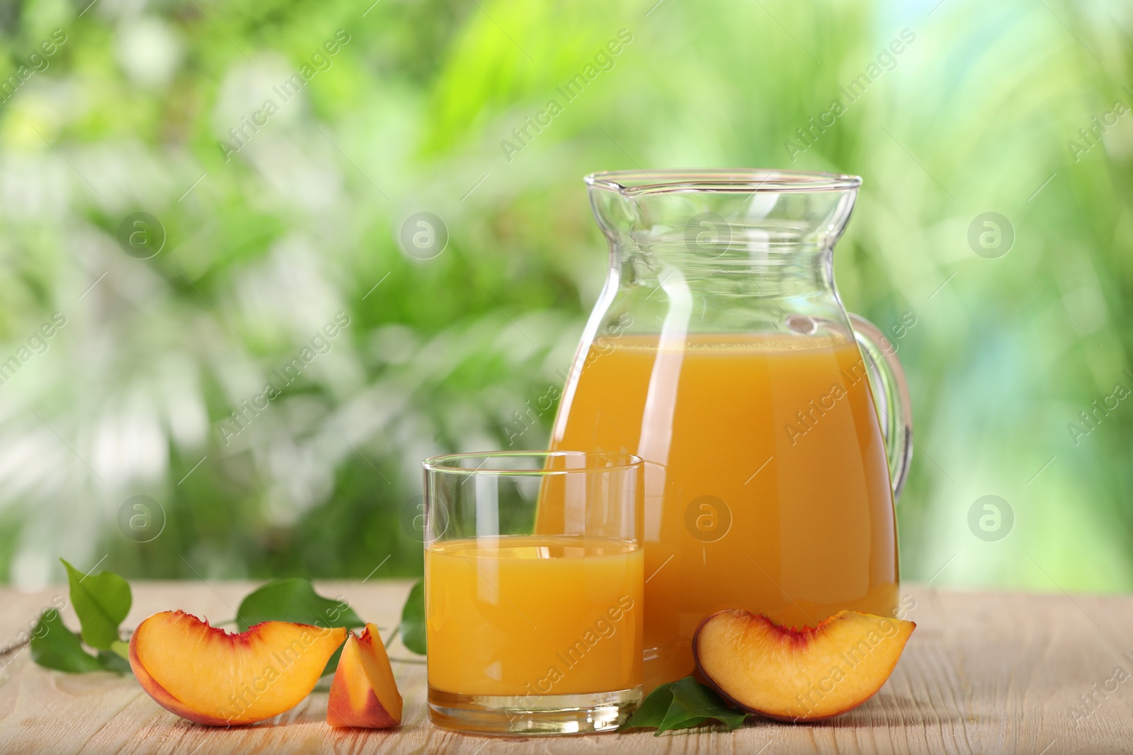 Photo of Tasty peach juice and fresh fruit on wooden table outdoors, space for text