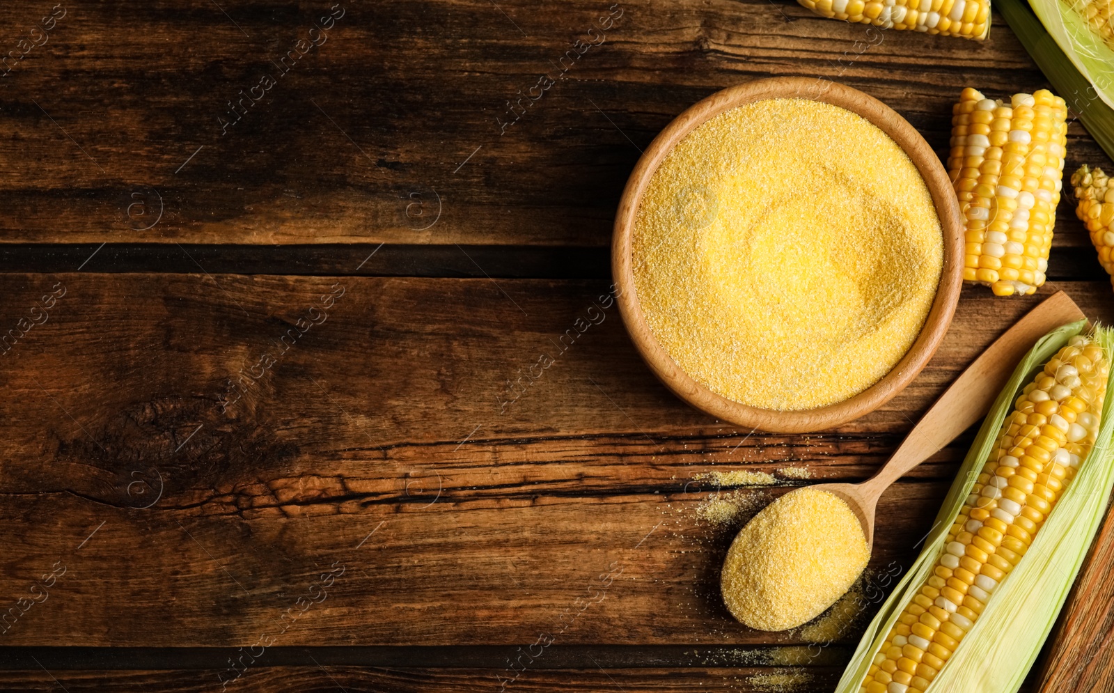 Photo of Flat lay composition with cornmeal and fresh cobs on wooden table, space for text