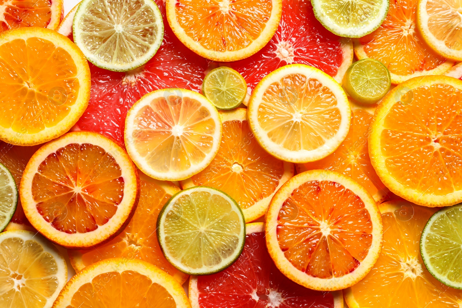 Photo of Slices of fresh citrus fruits as background, top view