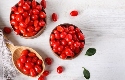 Flat lay composition with fresh ripe goji berries on white wooden table