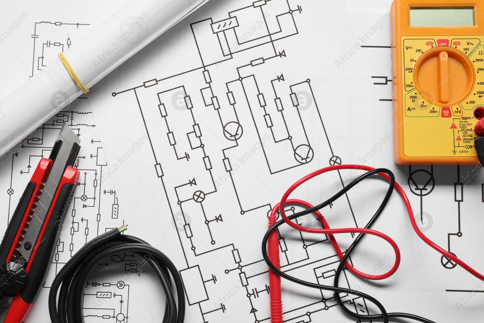 Photo of Wires and digital multimeter on wiring diagrams, top view