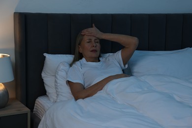 Woman suffering from headache in bed at night