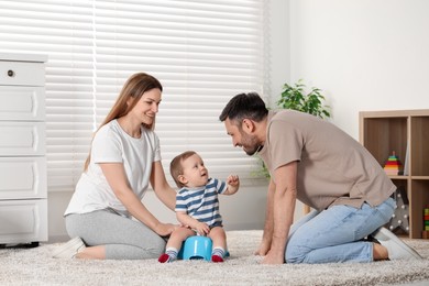 Parents training their child to sit on baby potty indoors