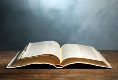 Photo of Open Bible on wooden table against color background. Christian religious book