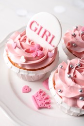 Delicious cupcakes with pink cream and Girl topper for baby shower on plate, closeup