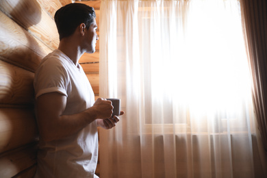 Man with drink near window indoors. Lazy morning