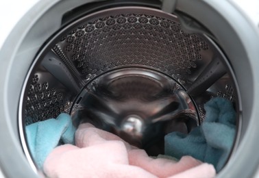 Photo of Modern washing machine drum with laundry, closeup