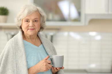 Photo of Elderly woman with cup of tea in kitchen. Space for text