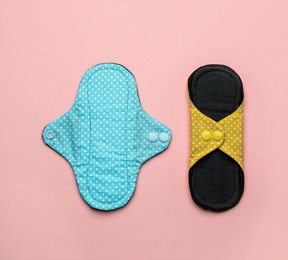Reusable cloth menstrual pads on pink background, flat lay