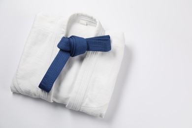 Photo of Blue karate belt and kimono on white background, top view. Space for text