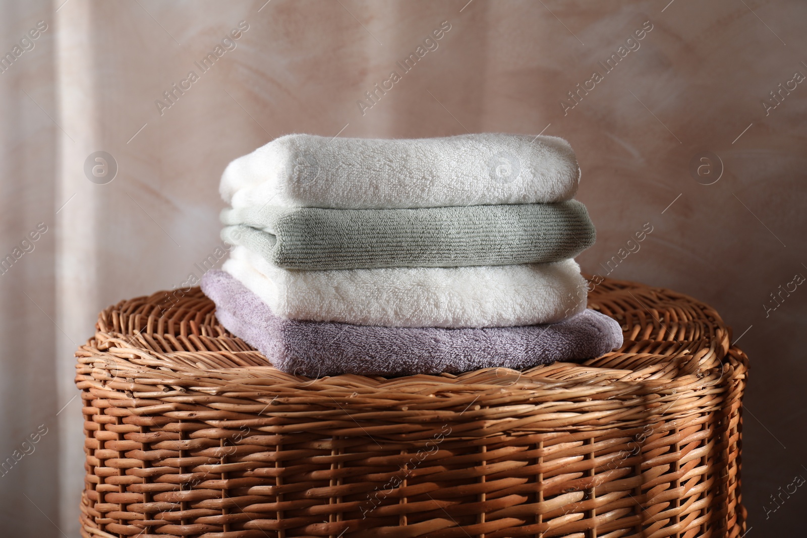 Photo of Stacked soft towels on rattan laundry basket indoors