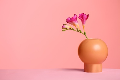 Photo of Stylish vase with beautiful flower on table against color background, space for text