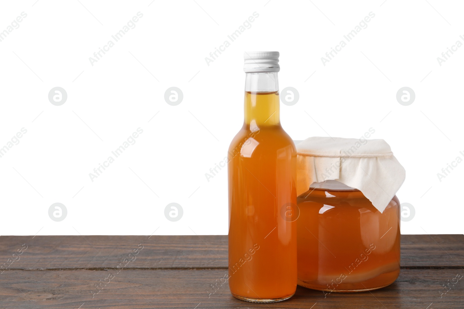 Photo of Delicious kombucha in glass bottle and jar on wooden table against white background, space for text