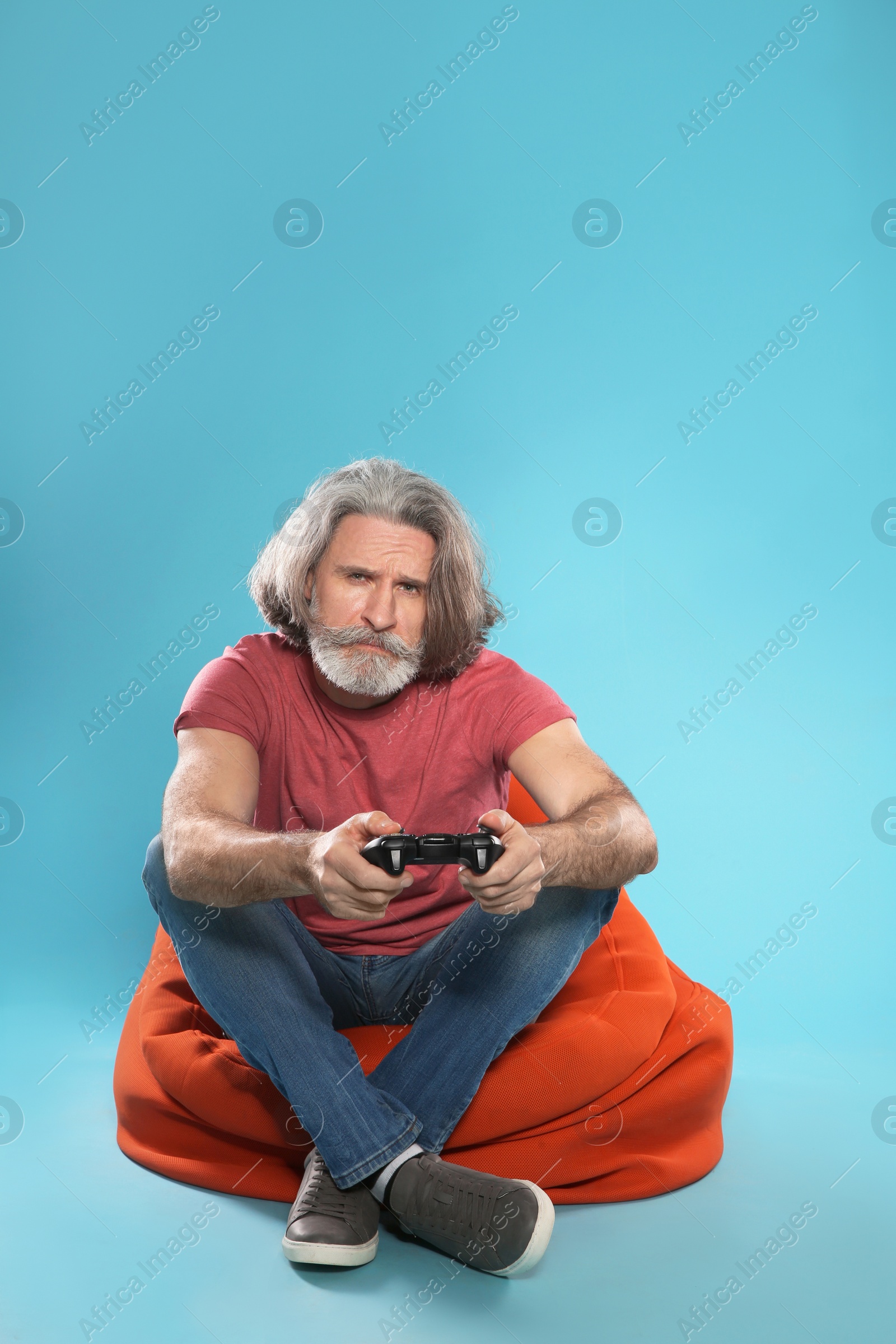 Photo of Emotional mature man playing video games with controller on color background. Space for text