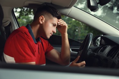 Photo of Stressed man in driver's seat of modern car