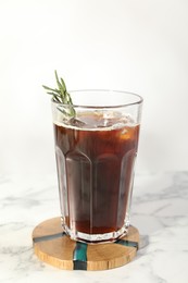 Photo of Refreshing iced coffee with rosemary in glass on white marble table