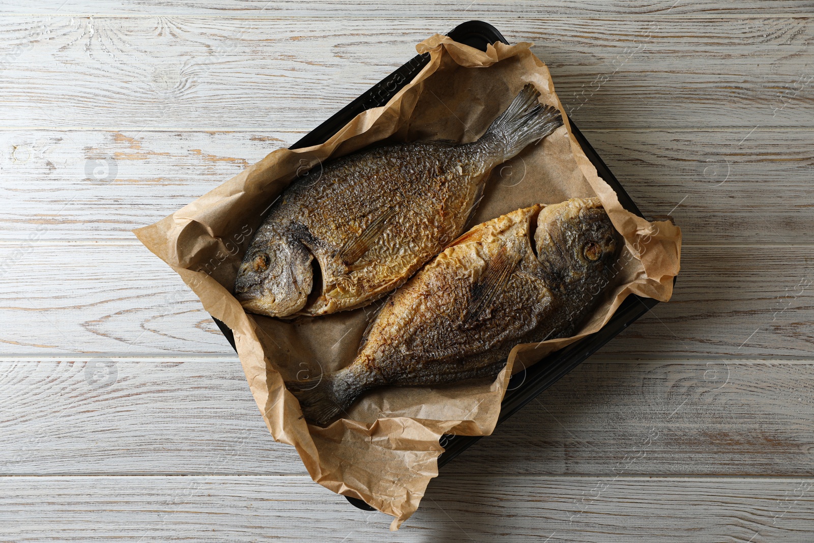 Photo of Delicious roasted dorado fish on wooden table, top view