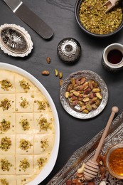 Photo of Making delicious baklava. Raw dough with ingredients on black textured table, flat lay