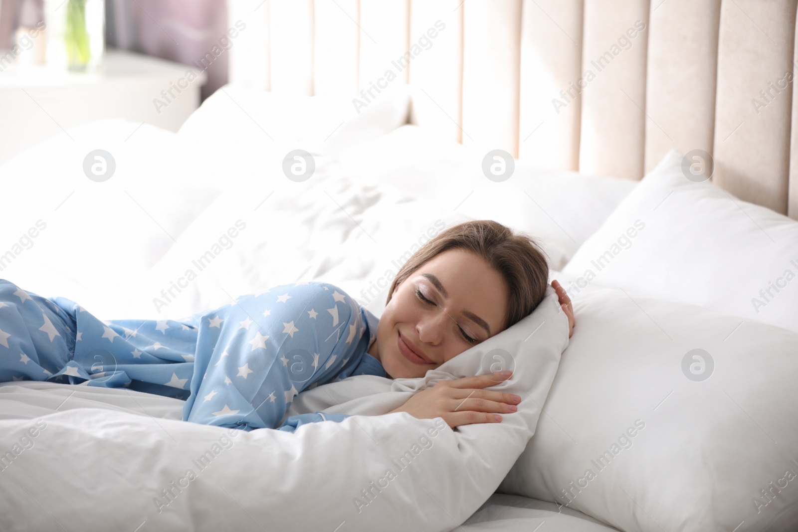 Photo of Young woman sleeping on comfortable pillow in bed at home