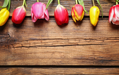 Photo of Beautiful spring tulips on wooden background, flat lay. Space for text