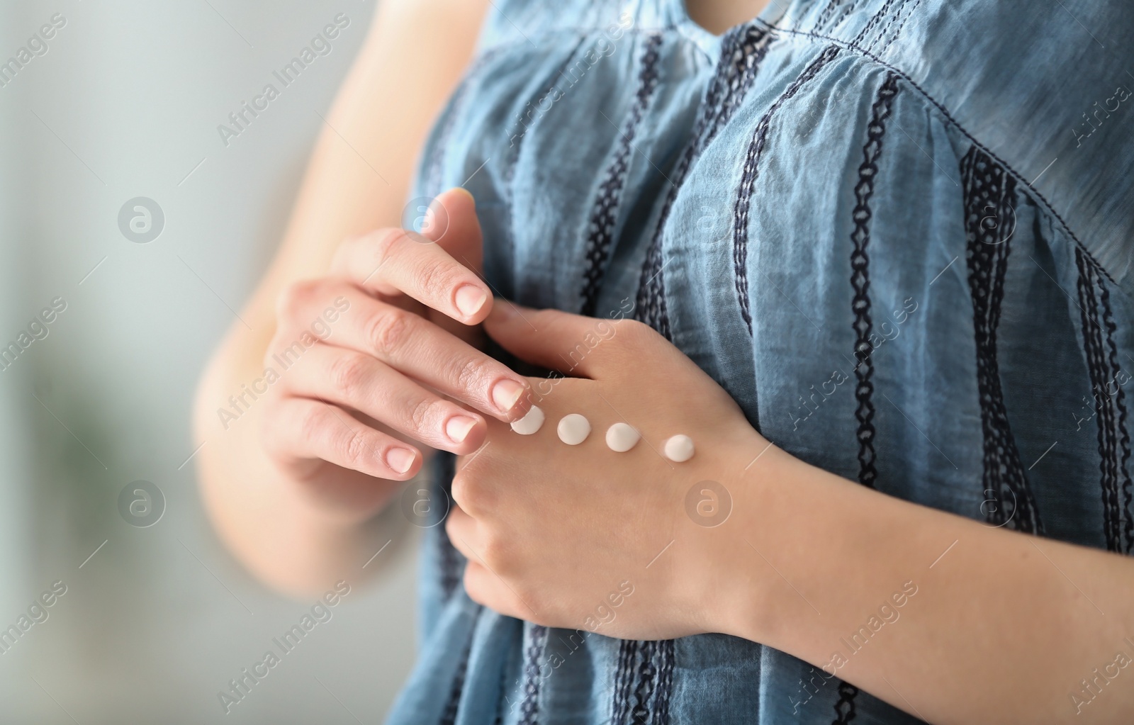 Photo of Young woman applying hand cream at home, closeup