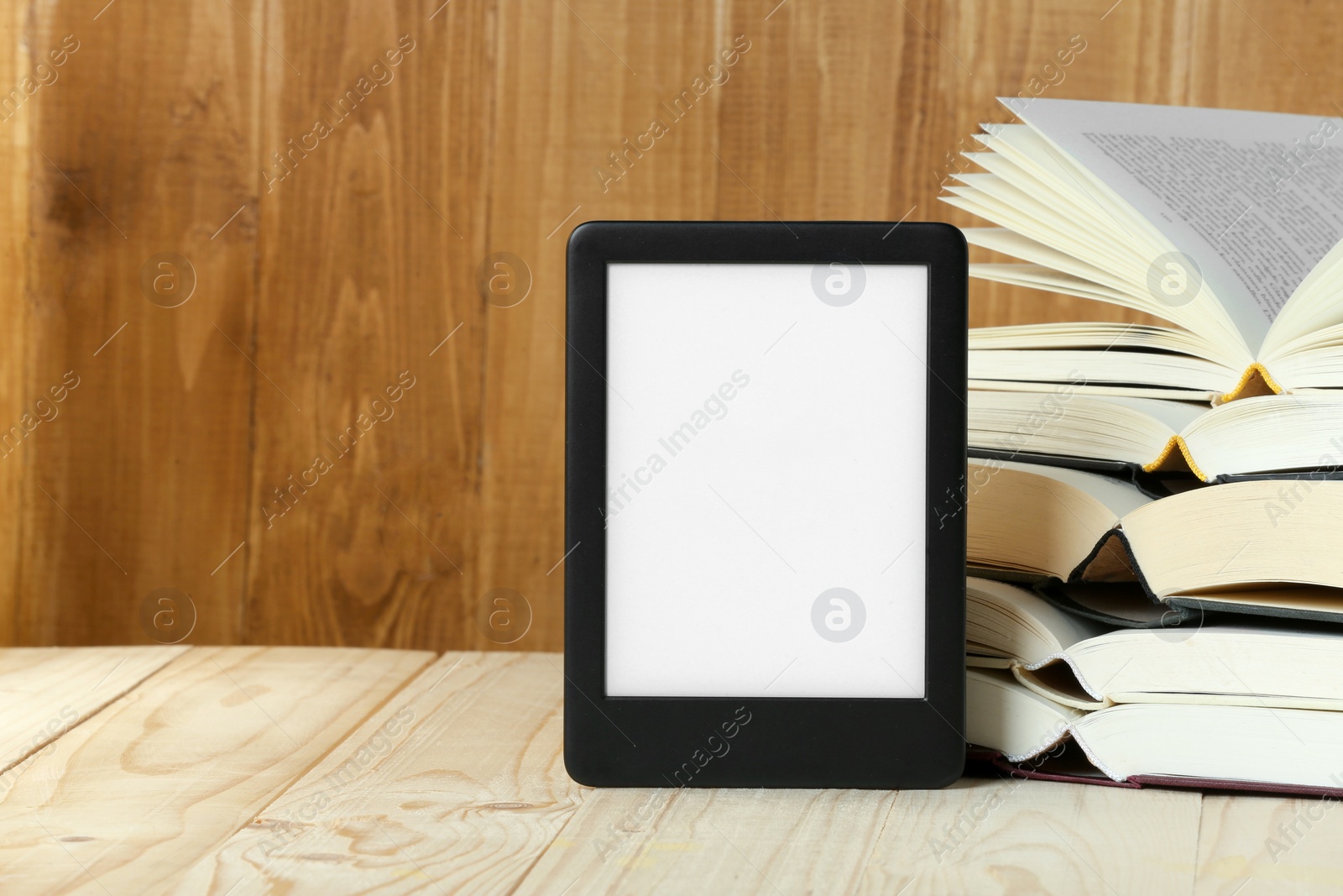 Photo of Portable e-book reader and open hardcover books on wooden rustic table, space for text