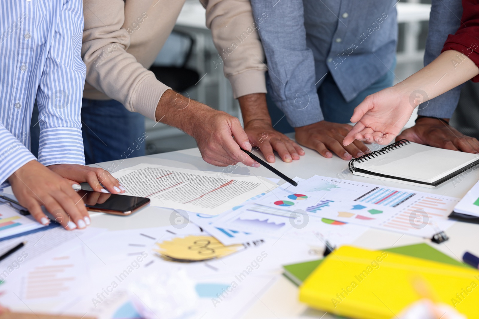 Photo of Team of employees working with charts at table, closeup. Startup project