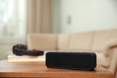 Photo of One black portable bluetooth speaker on wooden table indoors, space for text. Audio equipment