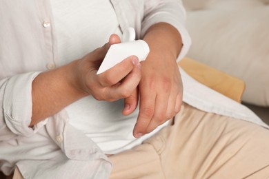 Photo of Man applying hand cream from tube at home, closeup