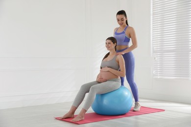 Photo of Trainer working with pregnant woman in gym. Preparation for child birth