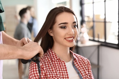 Photo of Professional hairdresser working with client in beauty salon