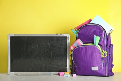 Photo of Small chalkboard and backpack with different school stationery on table