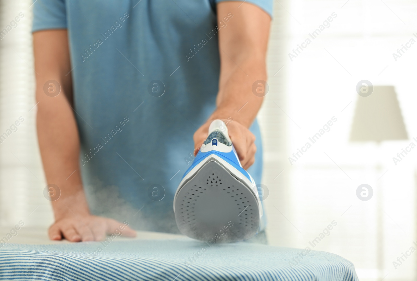 Photo of Handsome man ironing clean laundry at home, closeup
