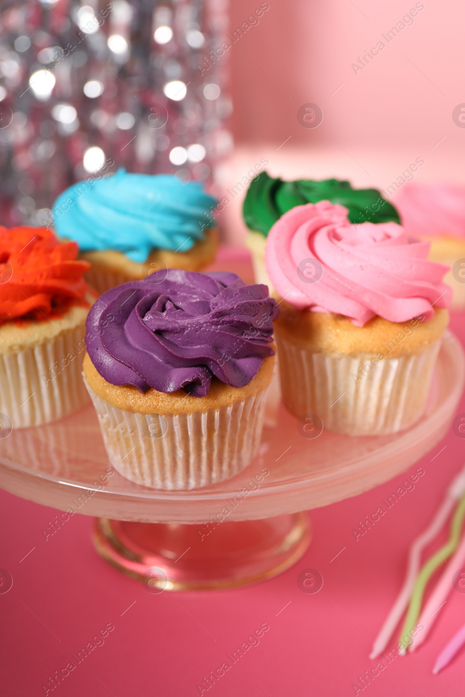 Photo of Delicious cupcakes with bright cream on pink table, closeup