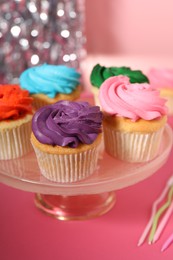 Photo of Delicious cupcakes with bright cream on pink table, closeup