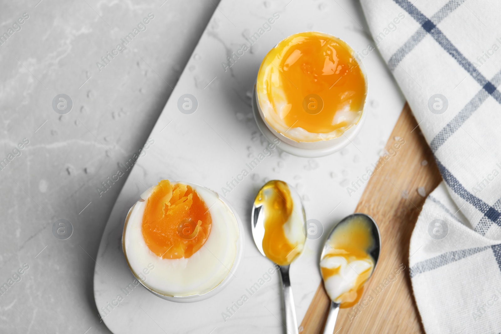 Photo of Soft and medium boiled chicken eggs on light grey marble table, flat lay