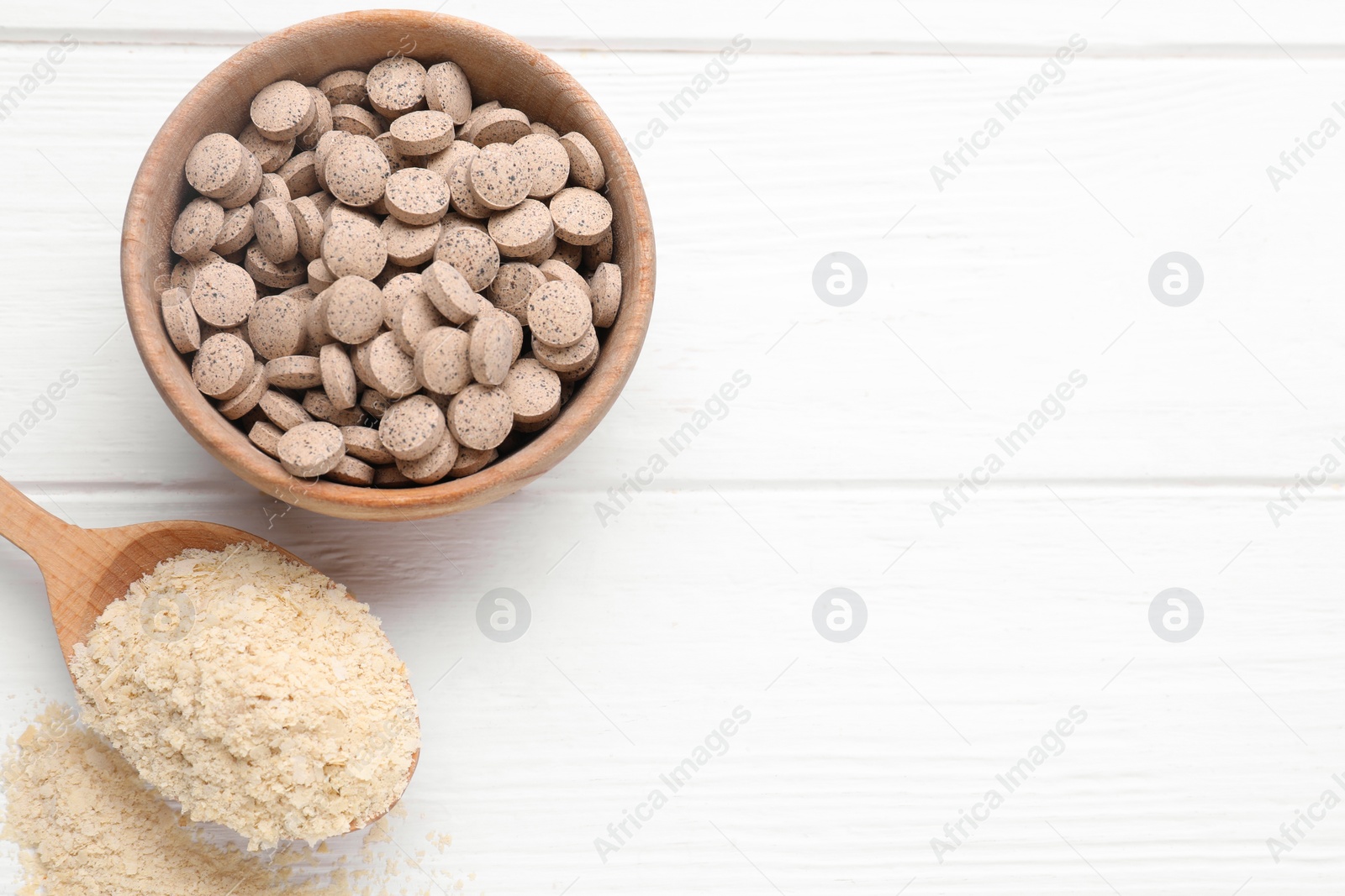 Photo of Beer yeast flakes and pills on white wooden table, flat lay. Space for text