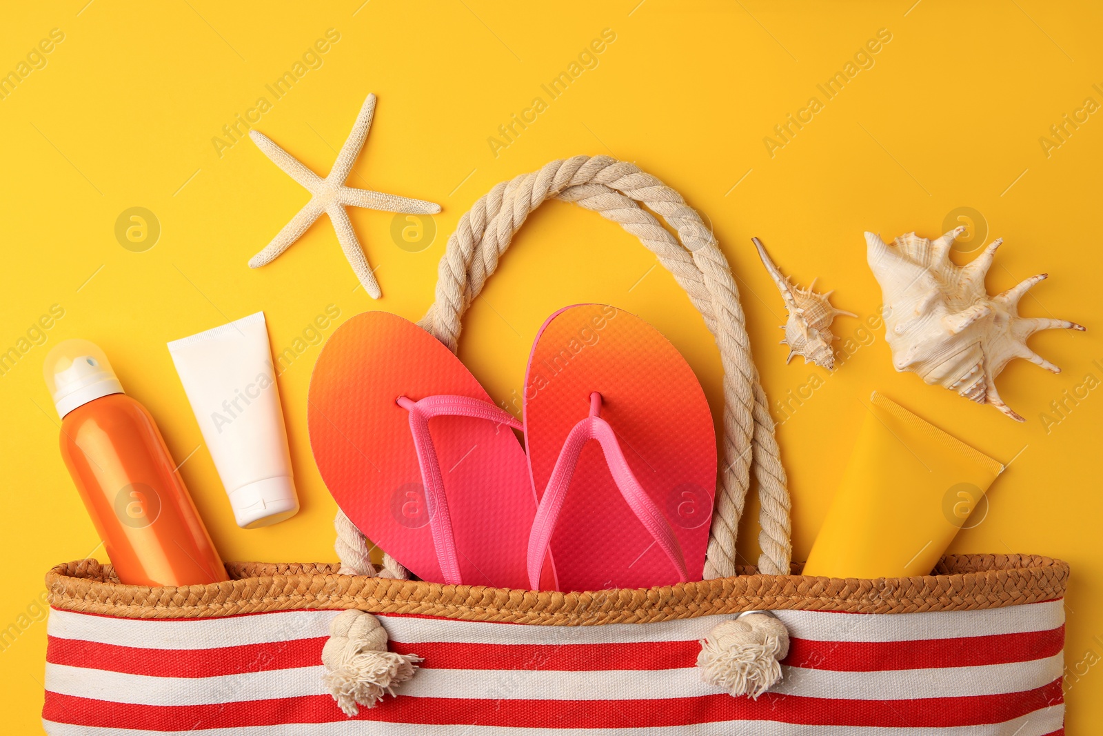 Photo of Flat lay composition with sunscreen and beach accessories on orange background