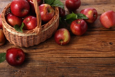 Fresh ripe red apples and leaves on wooden table. Space for text