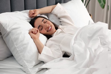 Photo of Happy woman awakening in bed at home. Lazy morning