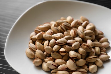 Many tasty pistachios on black table, closeup view
