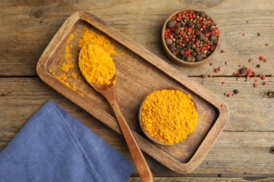Photo of Saffron powder and peppercorns on wooden table, flat lay