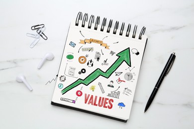 Concept of core values. Notebook with different images on white marble table, flat lay