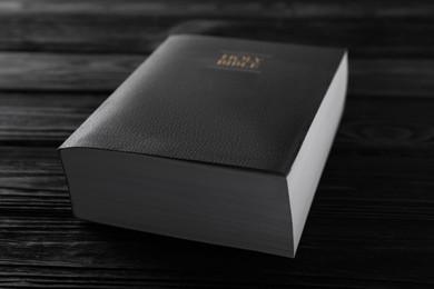 Photo of Bible on black wooden table, closeup. Christian religious book