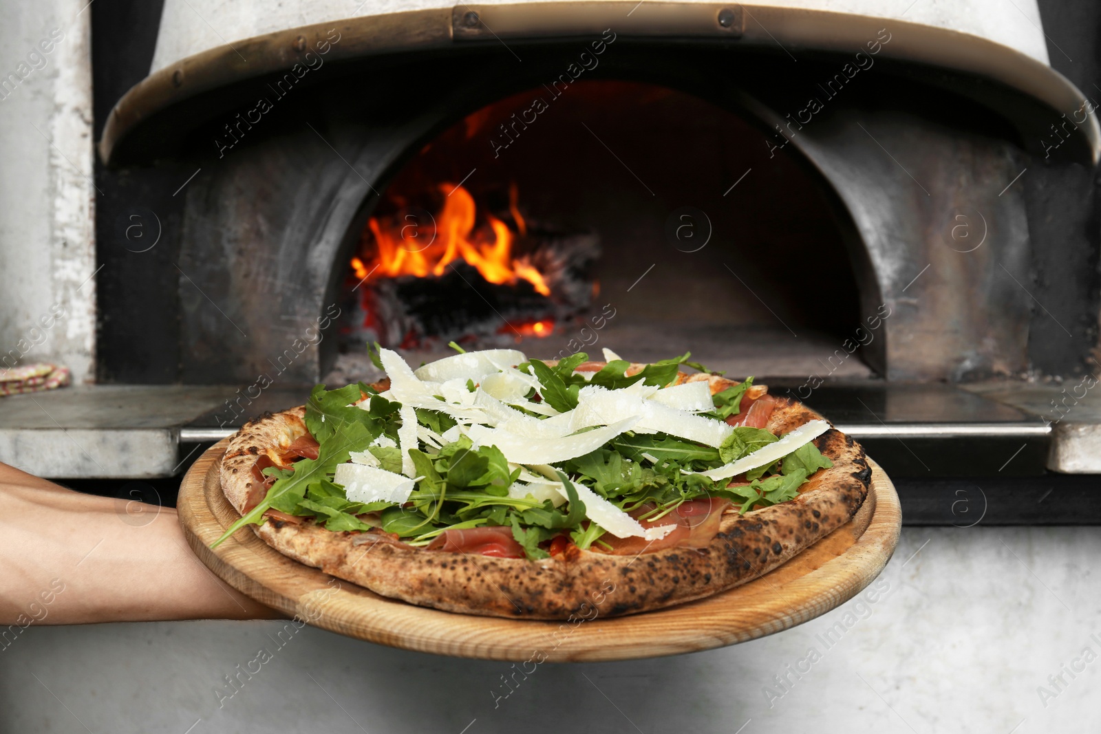 Photo of Professional chef holding tasty Italian pizza near oven in restaurant, closeup